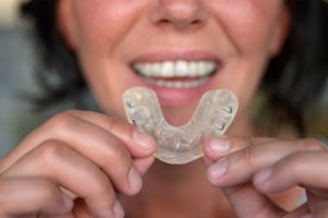 a close-up of a woman holding a clear plastic retainer